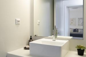 a white bathroom with a sink and a mirror at Lagadia Village in Antiparos