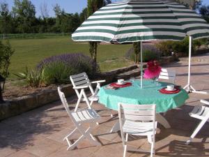 uma mesa com um guarda-sol verde e branco e cadeiras em La Motte Melleraye em Donnery