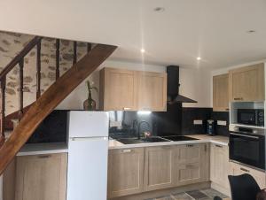 a kitchen with wooden cabinets and a white refrigerator at Maison agréable 4 à 6 pers in Aulon +8 photos