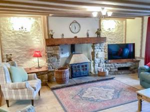 een woonkamer met een stenen open haard en een televisie bij Hadrians Wall Cottage, Greenhead in Greenhead