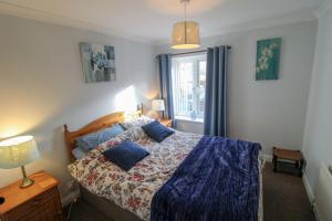 een slaapkamer met een bed met blauwe kussens en een raam bij Hadrians Wall Cottage, Greenhead in Greenhead