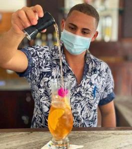 ein Mann mit Gesichtsmaske macht ein Getränk in der Unterkunft Hotel Espadarte in Iriri