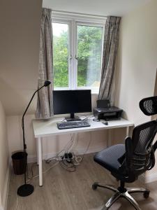 a desk with a computer on it in front of a window at Quiet studio flat near University & QMC, King size bed in Nottingham