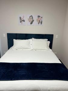 uma cama com uma cabeceira azul e três fotografias na parede em Apartamento na Montanha em Campos em Campos de Jordão