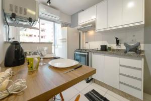 a kitchen with a wooden table and white cabinets at Apto Piscina Academia Ar Cond CID108C in Maringá