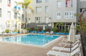 a swimming pool with lounge chairs and a hotel at Sardina Serena in Gáldar