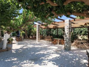 a patio with tables and chairs under a wooden umbrella at Vasilis Studios in Animborió