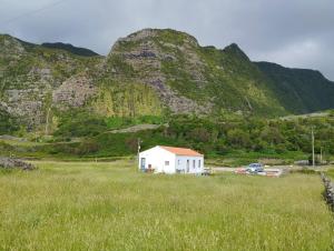 a white building in a field with a mountain at Casa do Branco in Faja Grande