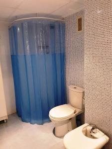 baño con aseo y cortina de ducha azul en Primera Linea Villa Oropesa Magic World - Marina D'Or, en Oropesa del Mar