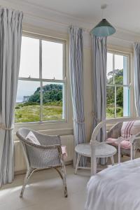 ein Schlafzimmer mit einem Bett und zwei Stühlen und Fenstern in der Unterkunft Mariner's Cottage by Coaste in Deal