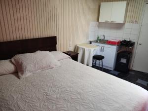a bedroom with a white bed and a kitchen at Alojamiento Saint Michell, El Quisco in El Quisco