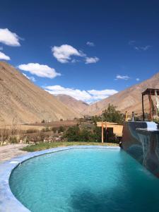 una piscina de agua azul con montañas en el fondo en Cabañas Elquimista en Pisco Elqui