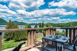 a table on a deck with a view of a lake at Lakefront Mountain View Remote Work - 1 Bd Suite in Lac-Superieur