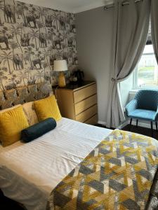 a bedroom with a bed with a blanket and a chair at The Blackhorse Accommodation in Newton Stewart