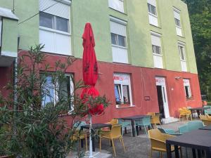 a building with tables and chairs and a red umbrella at Tifani Szálló in Balatonlelle