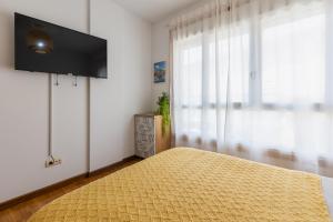 a bedroom with a bed and a flat screen tv at Piso A Pie de Playa - A Corna in San Pedro