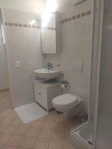 a white bathroom with a toilet and a sink at Casa Renoir - Schritte zum Zee in Locarno +15 photos