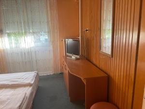 a bedroom with a desk with a television on it at Tifani Szálló in Balatonlelle