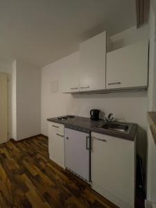 a small kitchen with white cabinets and a sink at Budget Studio - 2 Einzelbetten - Parkplatz in Dornbirn