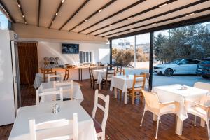 a restaurant with white tables and chairs and a car outside at Hotel Four Islands in Ksamil