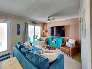 a living room with a blue couch and a tv at Tropical Winds - Ferda Buoys in Carolina Beach