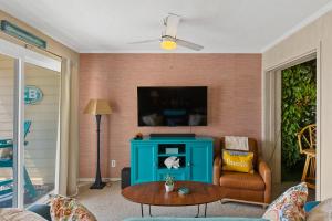 a living room with a blue cabinet and a tv at Tropical Winds - Ferda Buoys in Carolina Beach