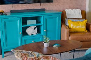 a blue cabinet in a living room with a table at Tropical Winds - Ferda Buoys in Carolina Beach +53 photos