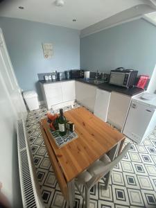 a kitchen with a wooden table with a bottle of wine at Bay View Apartment in Newbiggin-by-the-Sea