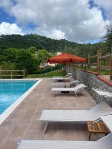 a patio with an umbrella and chairs and a pool at Podere il Glicine Wellness Charme & Relax in Fresonara