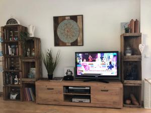 een televisie op een houten entertainmentcentrum in een woonkamer bij Albir Adventino LOVE in Albir