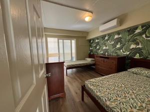 1 dormitorio con 2 camas, ventana y puerta en Waikiki Beachside Hostel en Honolulu