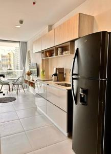 Il comprend une cuisine équipée d'un réfrigérateur noir et d'une table. dans l'établissement Loft vista mar terraza jacuzzi, à Santa Marta