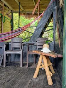 eine Veranda mit 2 Stühlen, einem Tisch und einer Hängematte in der Unterkunft Lodge El Amargal - Reserva Natural, Ecoturismo & Surf in Nuquí