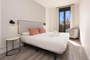 a bedroom with a large white bed and a window at Livemálaga Alta Suite & Parking in Málaga