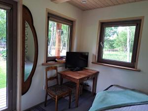 a room with a desk with a television and a mirror at Mugavustega majake kahele Muhumaal in Paenase