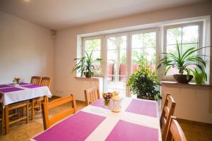 a dining room with purple and white tables and windows at Villa Jeziorki 71 in Warsaw