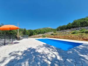 a swimming pool with an orange umbrella next to a patio at Apartment EMMA in Povile