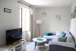 a living room with a couch and a tv at L'Escale - centre-ville et plage in Roscoff