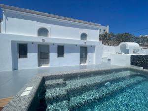 una villa con piscina di fronte a una casa di Solo Sole Suites Santorini a Éxo Goniá