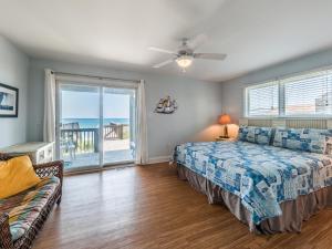 a bedroom with a bed and a couch and a window at Sand By Me in Surf City