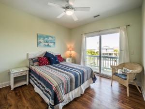 a bedroom with a bed and a balcony at Sand By Me in Surf City