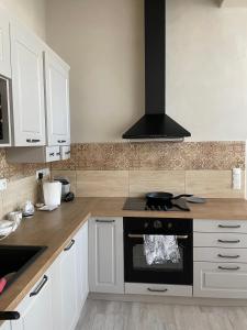a kitchen with white cabinets and a stove top oven at Apartmány Ľadovo in Lučenec +6 photos