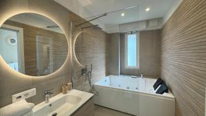 a bathroom with a tub and a sink and a mirror at Casa Febo, in centro con parcheggio privato a 200 mt dal mare in Bordighera
