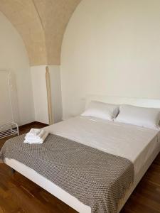 a bedroom with a large bed with white sheets at Casa Maria in Grottaglie
