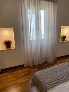 a bedroom with a window with white curtains and a wooden floor at Casa Maria in Grottaglie +7 photos