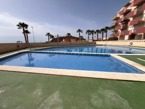 プエルト・デ・マサロンにあるRefugio de Paco, Primera Líneaのヤシの木が茂る建物の隣に大きなスイミングプールがあります。