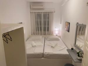 a white bedroom with two beds and a window at Votsalo in Ios Chora