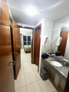 um banheiro com uma pia, um espelho e uma cama em Blue Sunset Beira Mar em João Pessoa