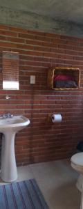 a bathroom with a white sink and a brick wall at Acogedor Bungalow en medio del bosque de Tepoztlan in Tlacotenco