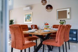 a dining room with a wooden table and orange chairs at Villa Mihojka in Malinska